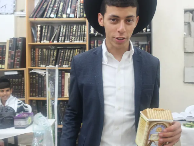 בחור מבני הקהילה מחזיק את קופת הצדקה של היכל יוסף שלום
